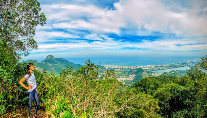 Woman overlooking scenic mountain view at Tijuca Forest peak.